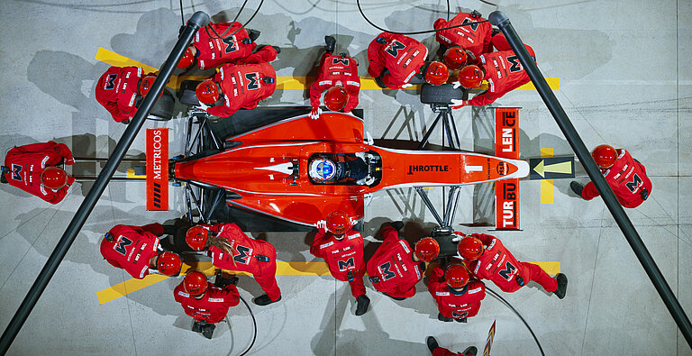 Formel 1 Crew von oben beim Boxenstopp mit Reifenwechsel